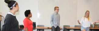 four people act out a skit in a classroom