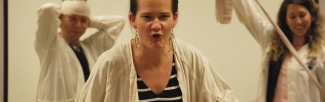 A person acts out a skit, their mouth in a roar and their hands raised