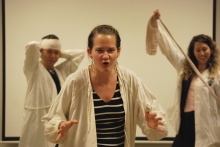 A person acts out a skit, their mouth in a roar and their hands raised